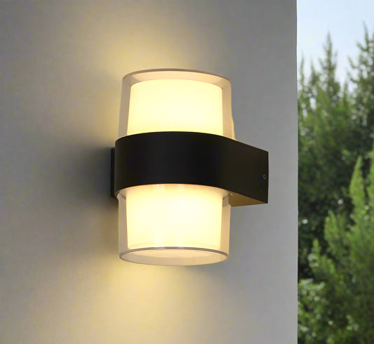 Wall-mounted light fixture with two cylindrical shades on a plain wall.