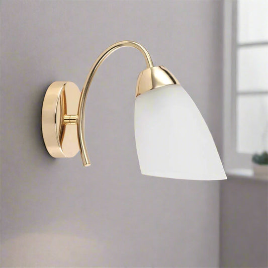 Wall-mounted light fixture with gold frame and white shade on a white background